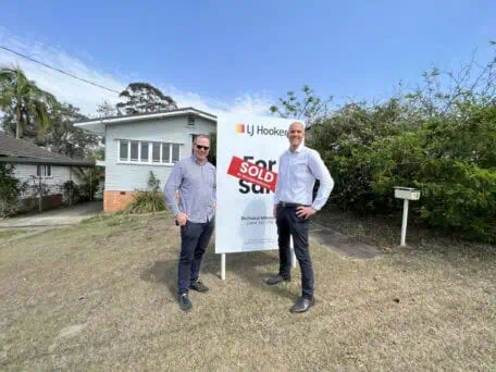 Sam Price and LJ Hooker agent standing outside a house purchased at Everton Park. 