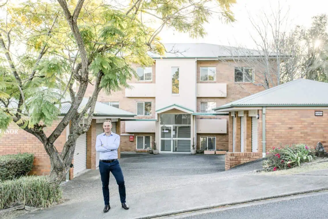 Sam Price standing in front of a property acquired for a client through auction bidding.